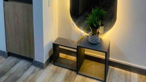 Une salle de bain moderne avec un grand miroir, un petit banc et une plante en pot.