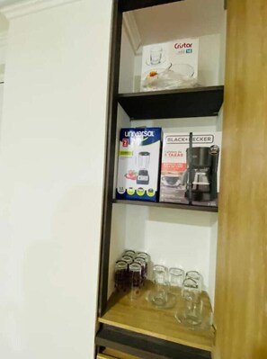 Een plank met een blender, een koffiezetapparaat en verschillende potten.