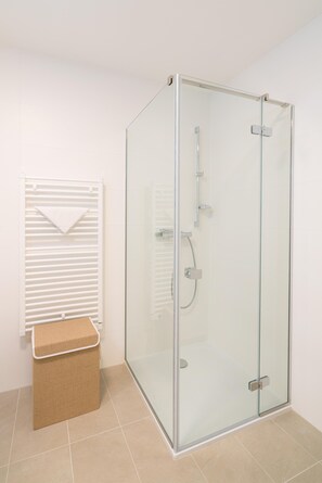 Une salle de bain moderne avec une douche à parois de verre, un porte-serviettes et un petit bac de rangement.