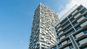 Ein Hochhaus mit modernem architektonischen Design, das mehrere Balkone und einen klaren Himmel im Hintergrund zeigt.