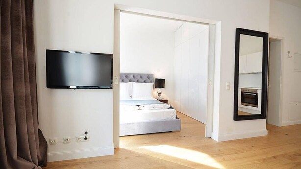Une chambre à coucher avec un lit, un téléviseur fixé au mur, un miroir et un four.