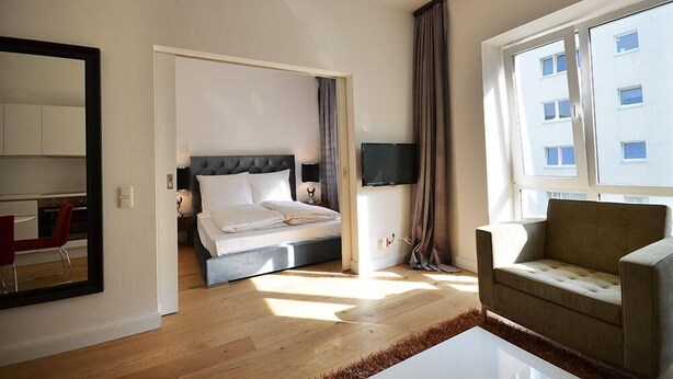 A modern hotel room with a bed, a TV, a sofa, and a large window. - Vienna Residence, Frankfurt - Schweizer Platz #6071 (Frankfurt)