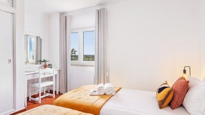 Una habitación de hotel con dos camas, un escritorio y una ventana con vistas.