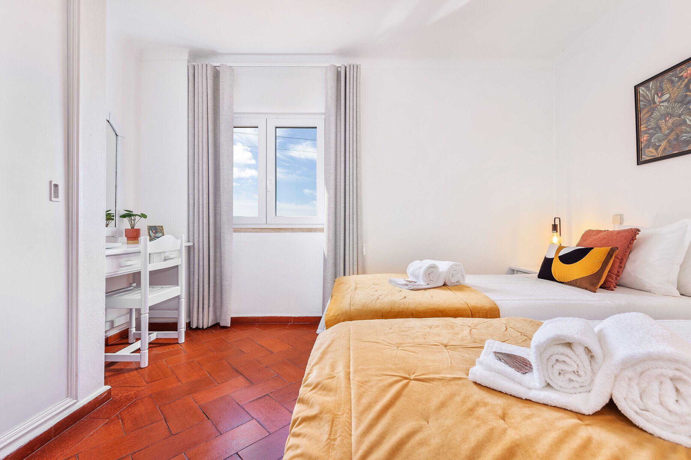 Una habitación de hotel con una cama, una ventana, una estantería con una planta y una puerta.