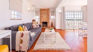 Una sala de estar con un sofá, una mesa de centro, una chimenea y vistas amplias a través de grandes ventanales.