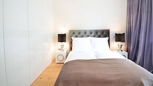 A neatly made bed with a tufted headboard, two bedside tables with lamps, and a large window with curtains. - Vienna Residence, Frankfurt - Schweizer Platz #6072 (Frankfurt)
