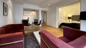 Un salon moderne avec des canapés rouges, un coin repas et une chambre à coucher équipée d’un lit et d’une télévision.
