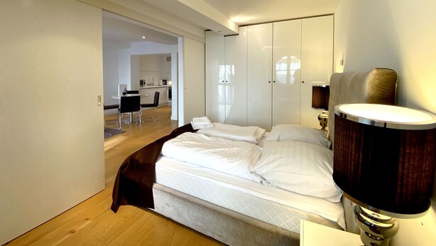 Une chambre d’hôtel moderne avec un grand lit, une lampe de chevet et une vue sur la cuisine.