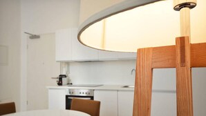 A modern kitchen with white cabinets, a round dining table, and a wooden chair. - Vienna Residence, Frankfurt - Schweizer Platz #6078 (Frankfurt)