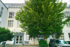 A building with a large tree in front, a parked car, and a clear sky. - Vienna Residence Frankfurt, Schweizer Platz #6078 (Frankfurt)
