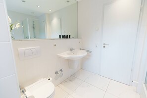Ein modernes Badezimmer mit Toilette, Waschbecken und Dusche.