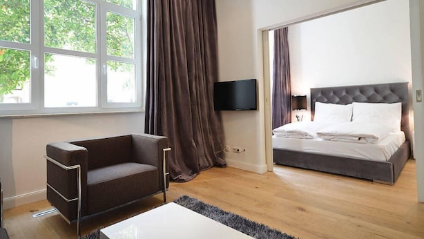 A modern bedroom with a sofa, a bed, a flat-screen TV, and large windows. - Vienna Residence, Frankfurt - Schweizer Platz #6083 (Frankfurt)