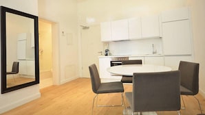 A modern kitchen with white cabinets, a round dining table, and four chairs. - Vienna Residence, Frankfurt - Schweizer Platz #6083 (Frankfurt)