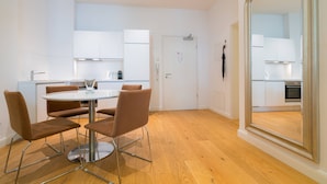 A modern kitchen with white cabinets, a round dining table with four chairs, and a large mirror. - Vienna Residence, Frankfurt - Schweizer Platz #6084 (Frankfurt)