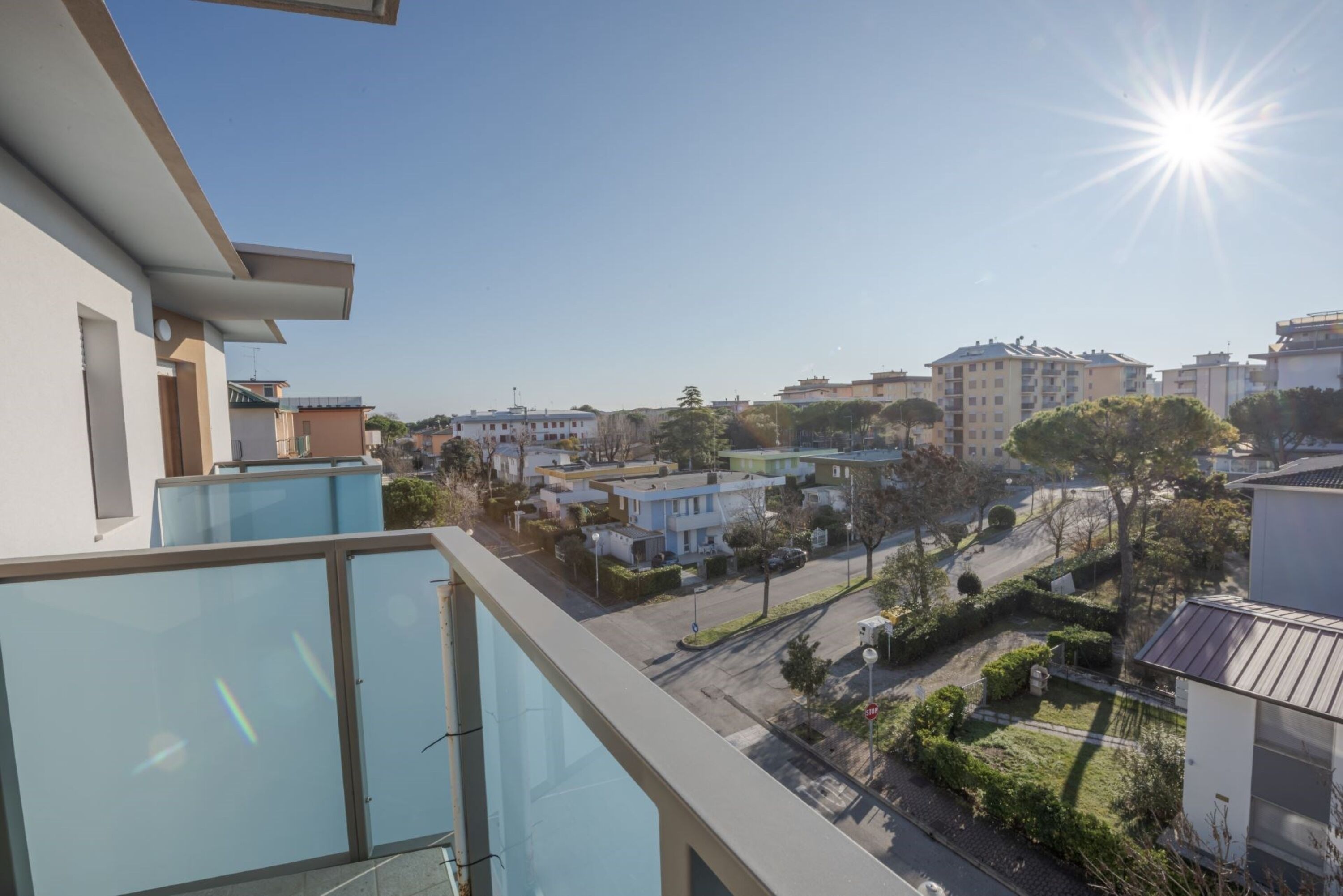 A residential area with modern buildings, a clear sky, and a bright sun.
