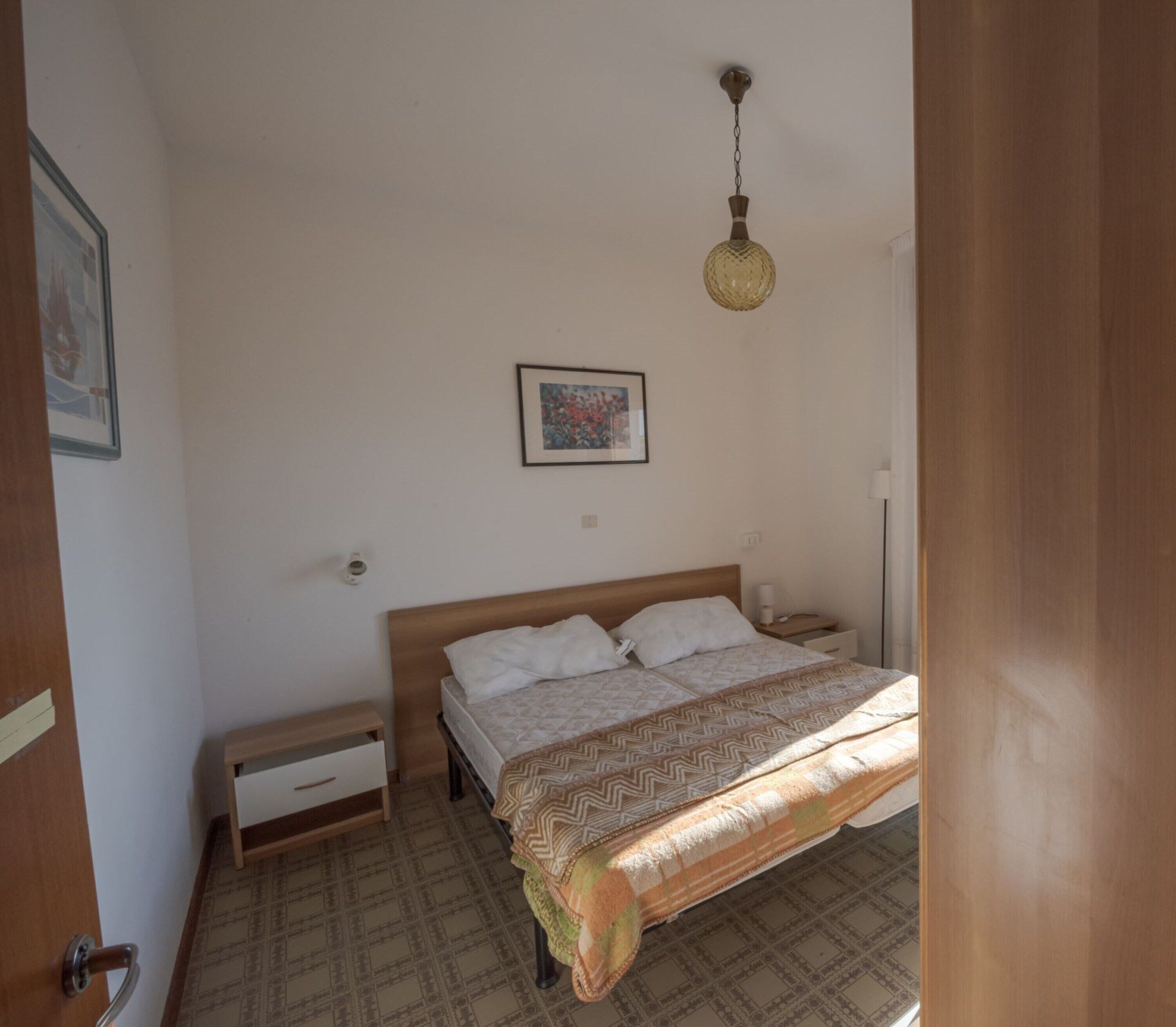 Une chambre à coucher avec un lit, une table de chevet et un luminaire suspendu.