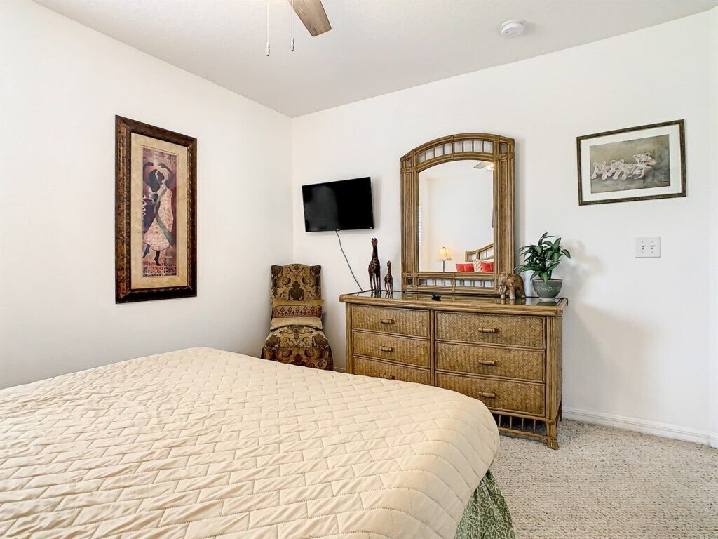 Quarto com cama, penteadeira, televisão e obras de arte na parede.