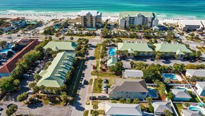 An aerial view of a coastal hotel with multiple buildings, a beach, and a parking area. - Great Location with Easy Beach Access! (Destin)