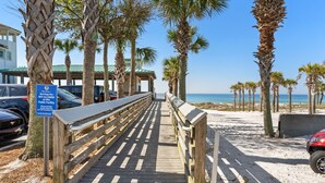 A wooden boardwalk leading to a beach with palm trees and parked cars. - Great Location with Easy Beach Access! (Destin)