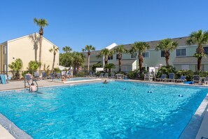 Ein Pool mit Liegestühlen und Palmen.
