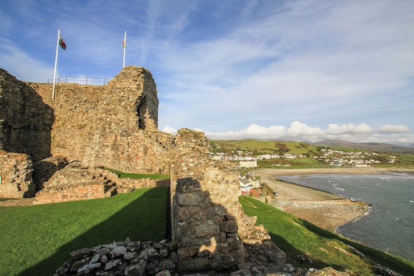 A historic stone structure with flags, overlooking a coastal town and beach.