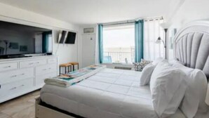 Un dormitorio moderno con cama, televisor, escritorio y ventana con cortinas.