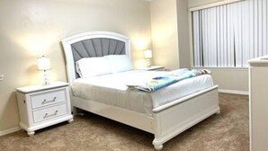 A bedroom with a bed, nightstand, and dresser. - 101 Bent Tree Modern Lux 2BR 2BA Heated Pool (Daytona Beach)
