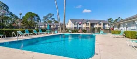 A swimming pool with lounge chairs and palm trees.