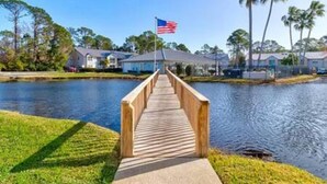 A wooden bridge leading to a row of houses by a body of water. - 101 Bent Tree Modern Lux 2BR 2BA Heated Pool (Daytona Beach)