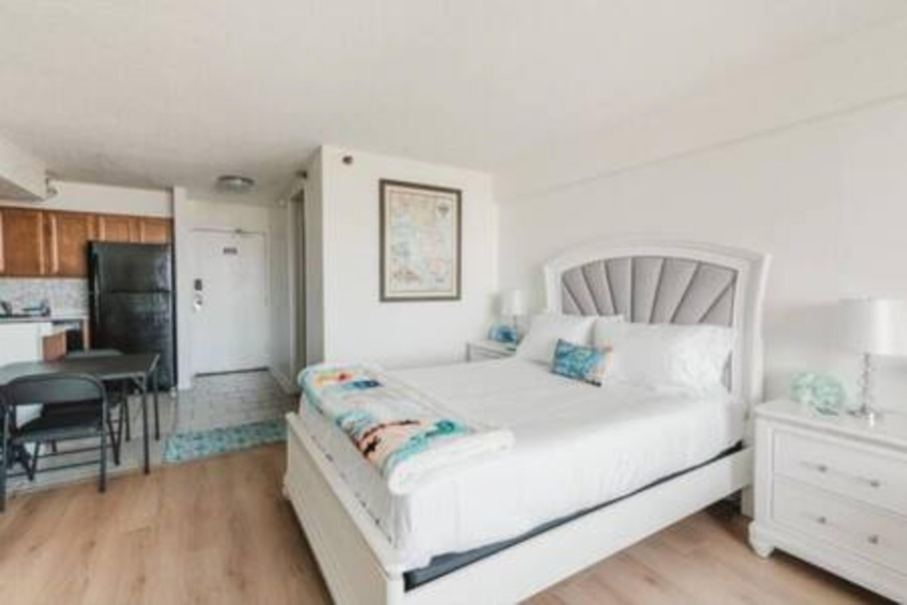 Un dormitorio con cama, mesita de noche y una pequeña zona de escritorio con silla.