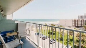 Ein Balkon mit Blick auf den Strand und einen Parkplatz.