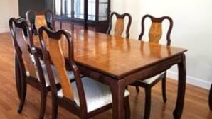 Ein Esszimmer mit Holztisch und -stühlen, einer Chandelüster und einem Schrank.