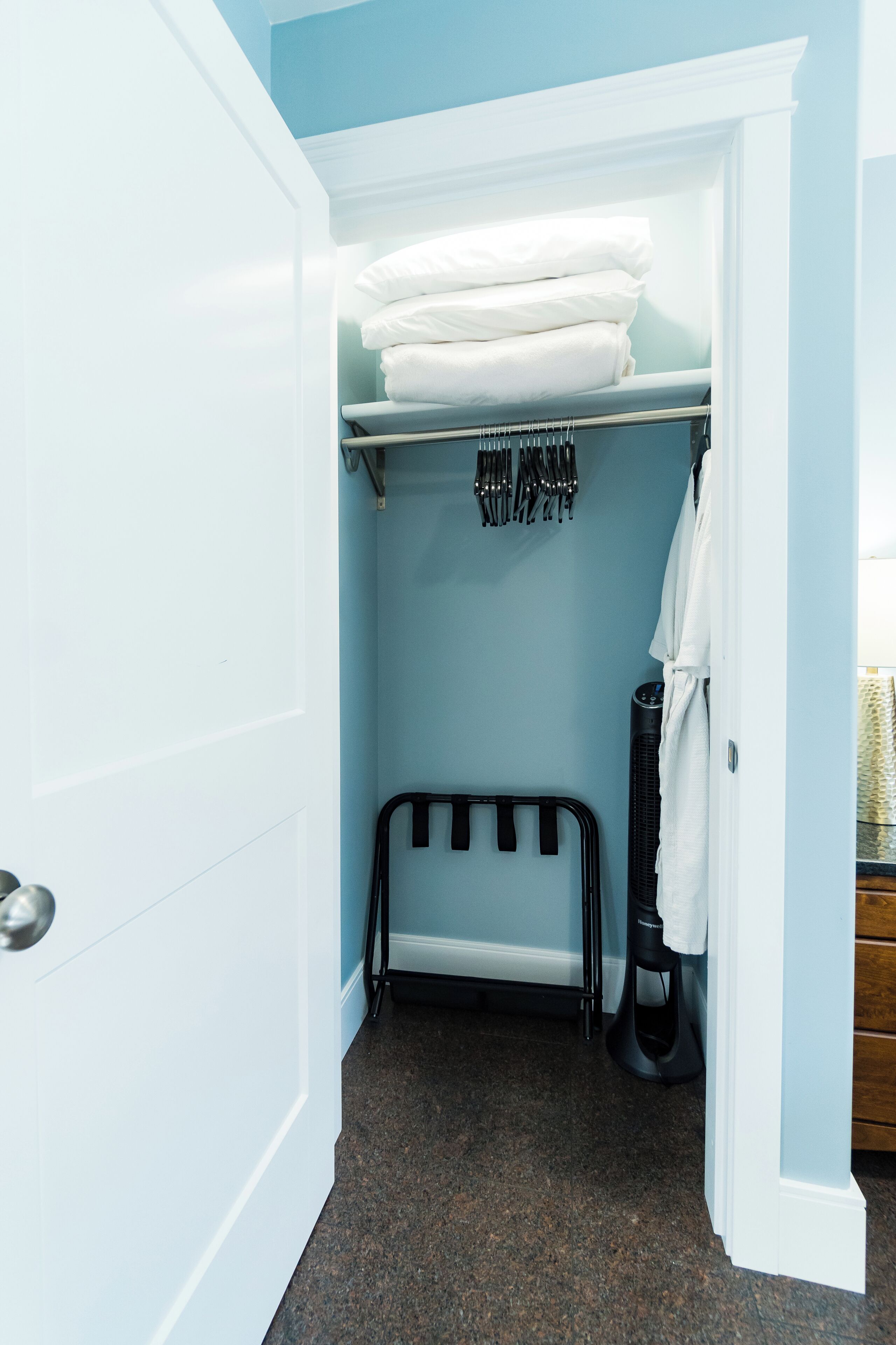 A bathroom with a blue wall, a towel rack with folded towels, a black radiator, and a white bath mat.