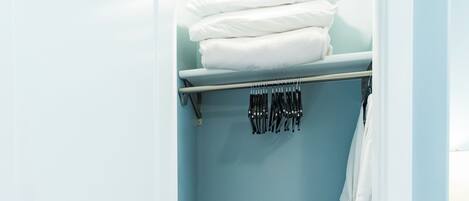 Une salle de bain avec un mur bleu, un porte-serviettes avec des serviettes pliées, un radiateur noir et un tapis de bain blanc.