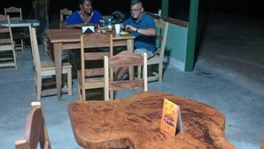 An outdoor seating area with wooden tables and chairs, a covered roof, and a sign on one table. - HOSTEL MAKTUB (Santa Rita)