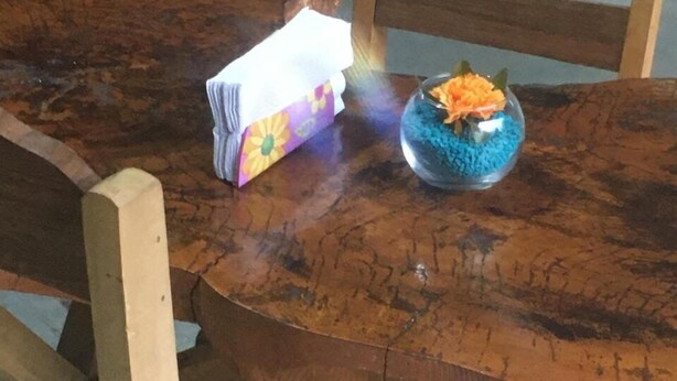 A wooden table with a tissue box and a glass bowl containing colorful items. - HOSTEL MAKTUB (Santa Rita)