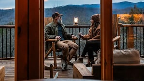 Une terrasse en bois avec deux chaises placées face à face, offrant une vue sur un paysage montagneux.