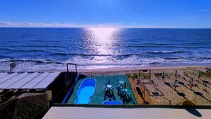 A beach view with a pool area, sun, and ocean. - Amazônia Praia Hotel (Tibau)