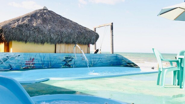 A pool area with a thatched-roof structure, lounge chairs, and a clear view of the ocean. - Amazônia Praia Hotel (Tibau)