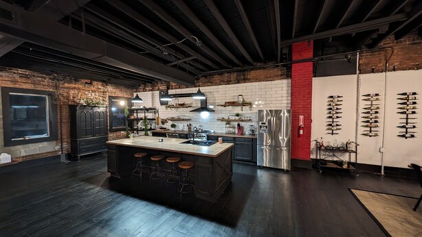 A modern kitchen with a central island, stainless steel appliances, and a brick wall. - Industrial urban Loft within 5 minutes from downtown (Highland Park)