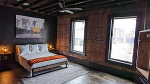 A bedroom with a bed, a cityscape painting, a window, and a ceiling fan. - Industrial urban Loft within 5 minutes from downtown (Highland Park)