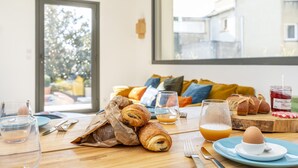 Et morgenbord med croissanter, et glas appelsinjuice, et glas vand, en tallerken med et hårdkogt æg og et syltetøjsglas.