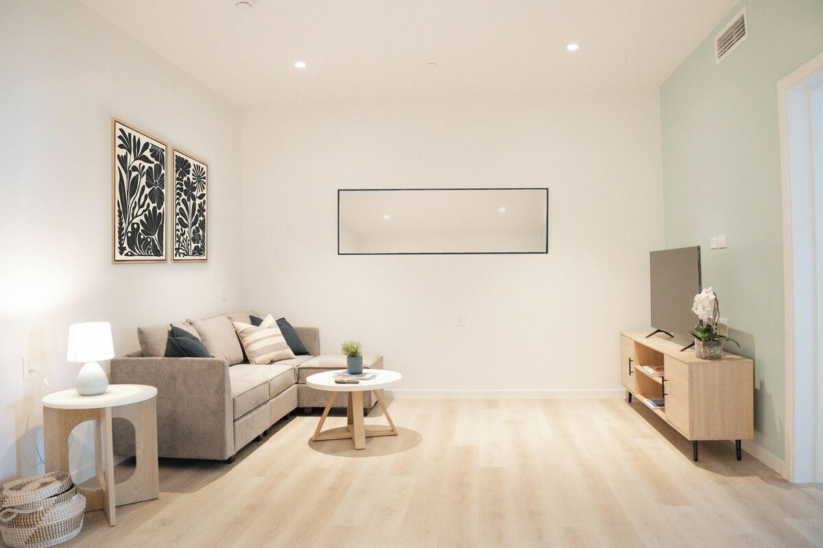 A modern living room with a sofa, a coffee table, a side table, a cabinet, and two wall-mounted artworks.