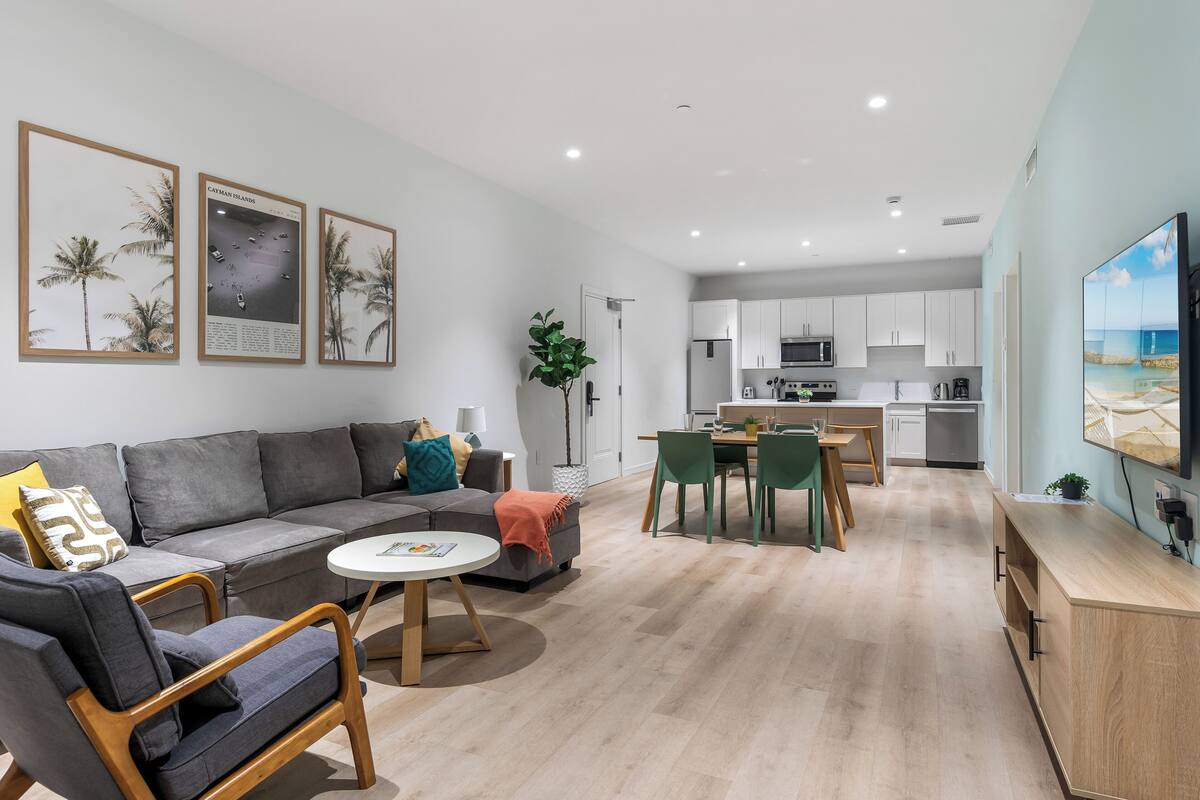 A modern living room with a grey sofa, a coffee table, and a dining area with a table and chairs.