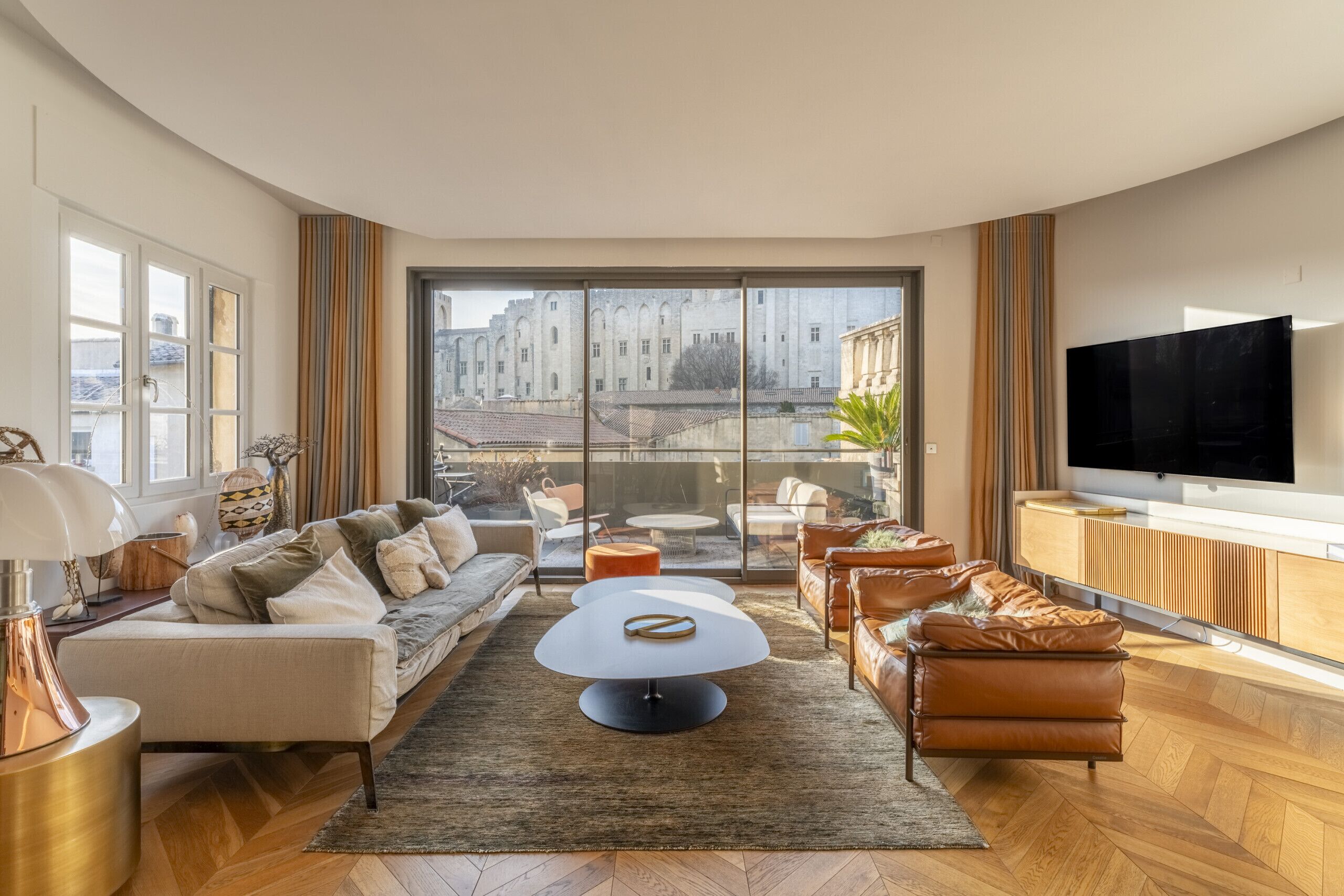 Un salon moderne doté d’une grande fenêtre, d’un téléviseur à écran plat et d’un ensemble de canapés.