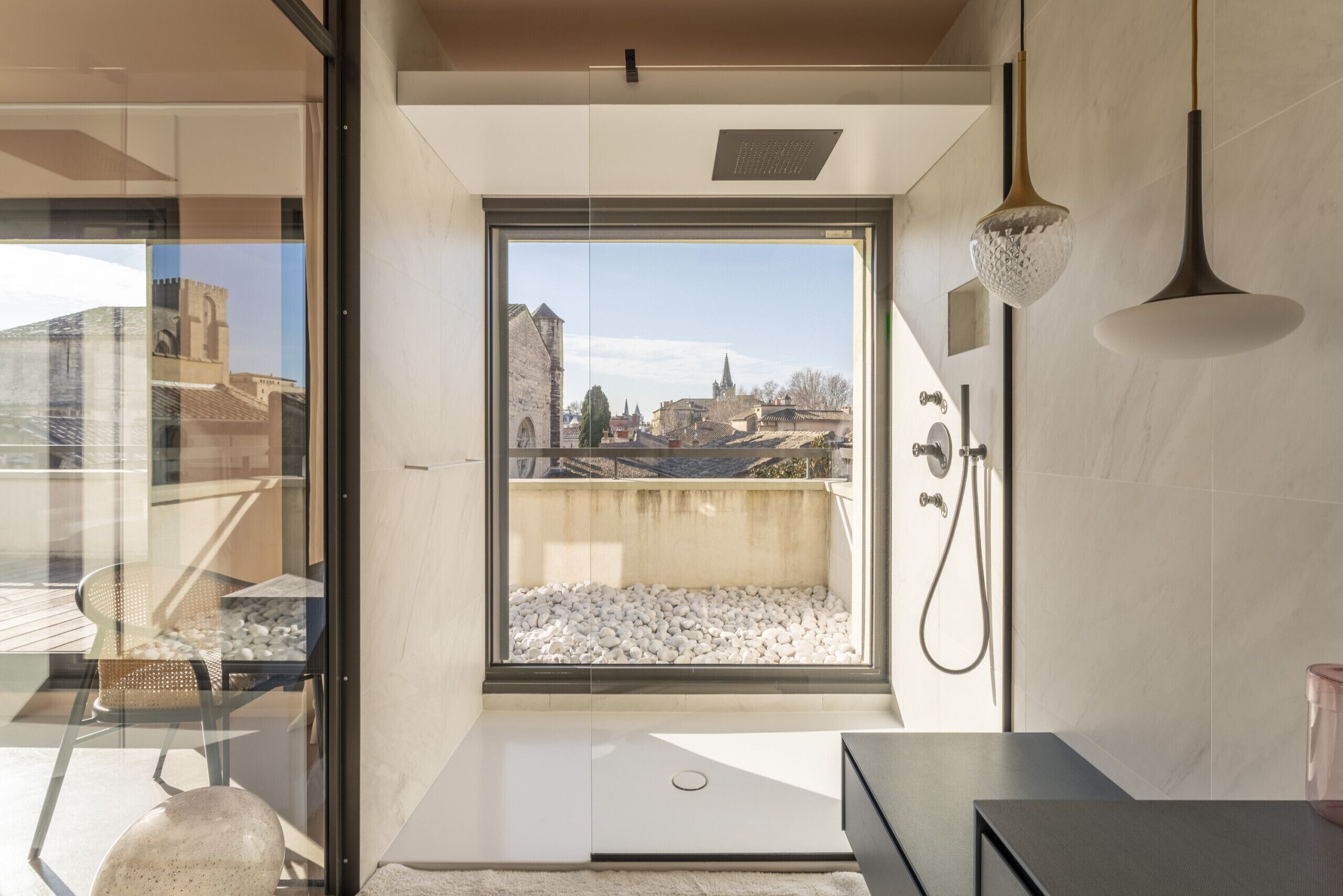 A modern bathroom with a large window, a shower, and a view of a cityscape.
