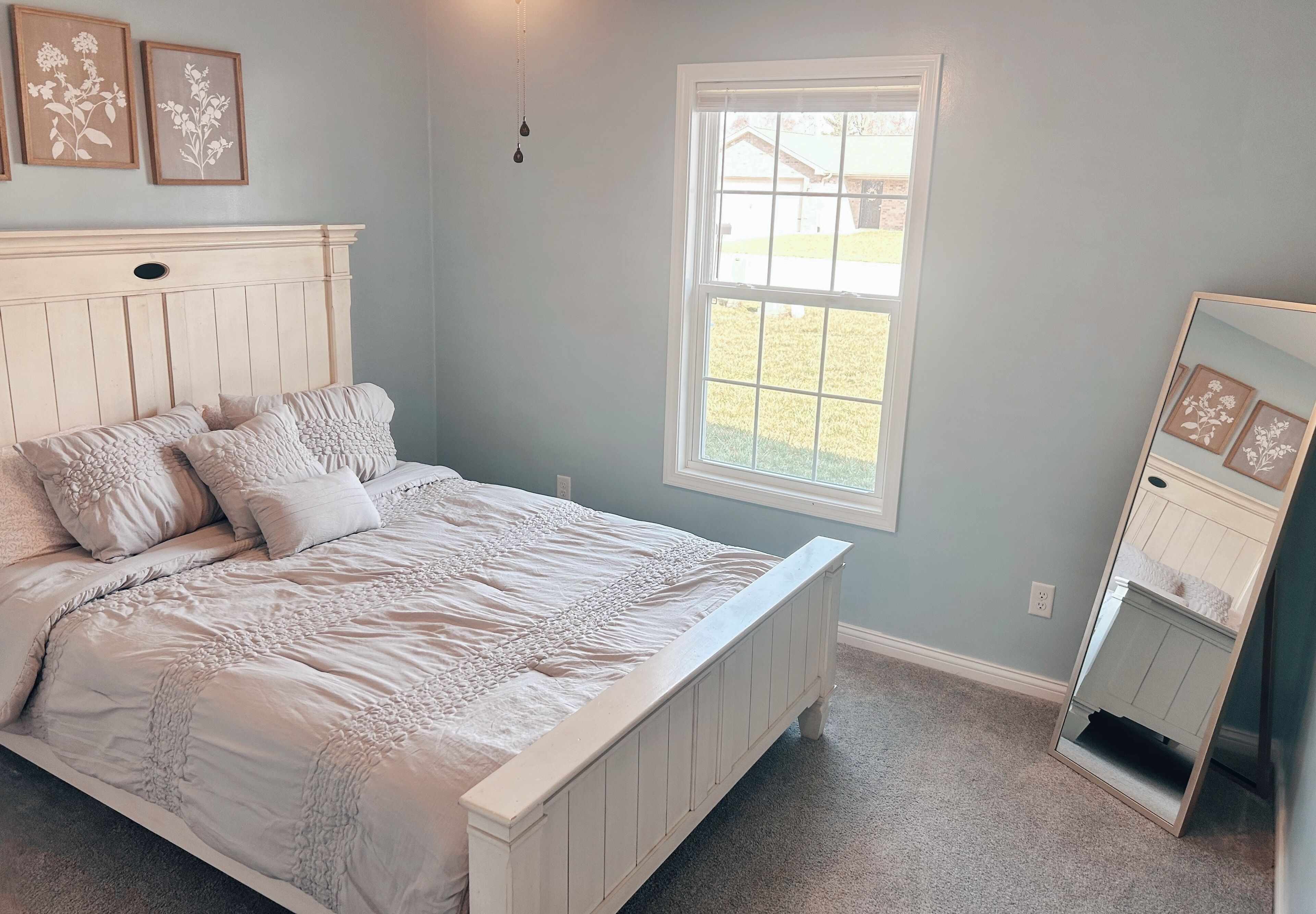 Un dormitorio con cama, ventana y espejo.