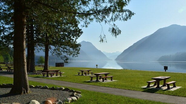 Een picknickplaats aan het meer met banken en een helder uitzicht op bergen.