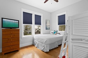 A bedroom with a bed, a dresser, a TV, and windows with blinds. - Lion on the Beach - Community Pool, Bikes + Golf Cart, Great 30A Locale! (Seagrove Beach)