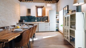 Una cocina moderna con una mesa de madera para cuatro comensales, armarios blancos y un horno empotrado.